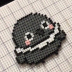 May include: A handmade pixel art cat face made from small grey, white, and pink beads. The cat features white whiskers, pink cheeks, and white eyes. The cat is set against a white grid background.